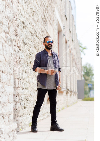 man with smartphone at stone wall on city street man with smartphone at stone wall on city street 25279987