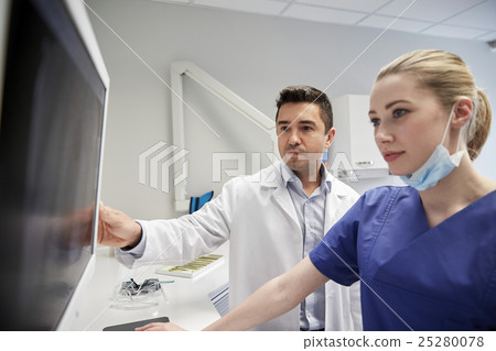 dentists with x-ray on monitor at dental clinic 25280078