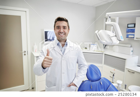 happy male dentist showing thumbs up at clinic 25280134