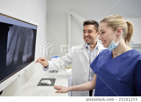 dentists with x-ray on monitor at dental clinic 25281255