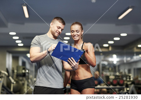smiling young woman with personal trainer in gym smiling young woman with personal trainer in gym 25281930
