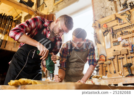 carpenters with drill drilling plank at workshop carpenters with drill drilling plank at workshop 25282088