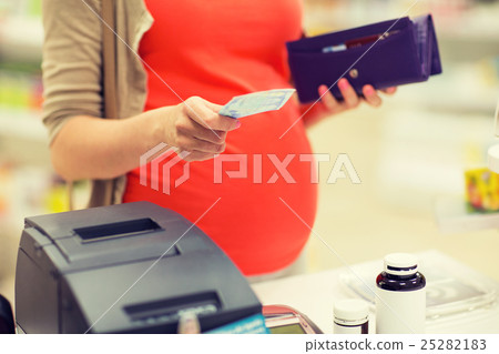 pregnant woman with money at cashbox in drugstore pregnant woman with money at cashbox in drugstore 25282183