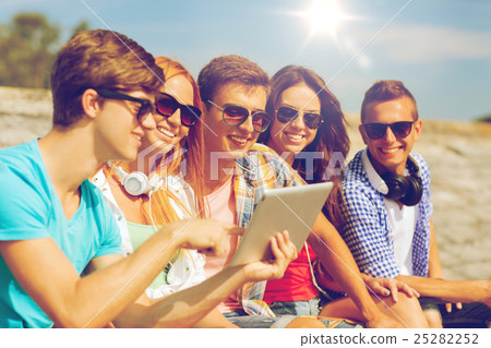 group of smiling friends with tablet pc outdoors 25282252