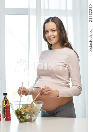 happy pregnant woman preparing food at home happy pregnant woman preparing food at home 25282259