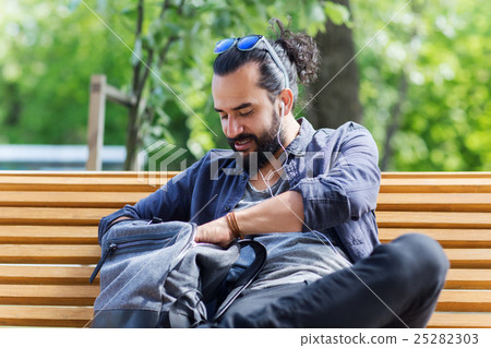 man with backpack and earphones in city 25282303