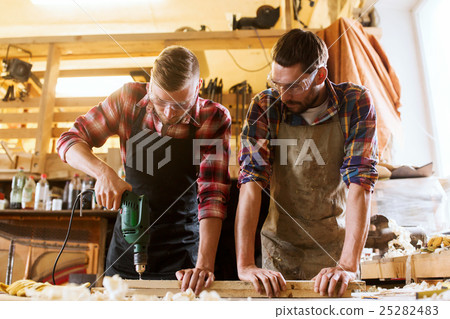 carpenters with drill drilling plank at workshop carpenters with drill drilling plank at workshop 25282483