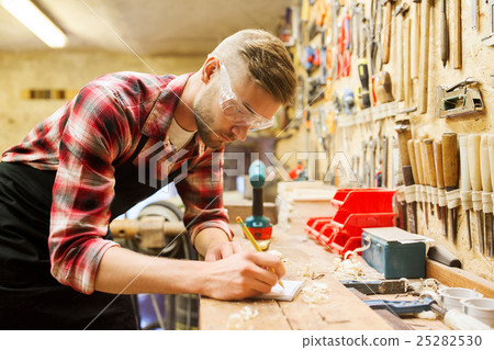 carpenter writing to notebook at workshop carpenter writing to notebook at workshop 25282530