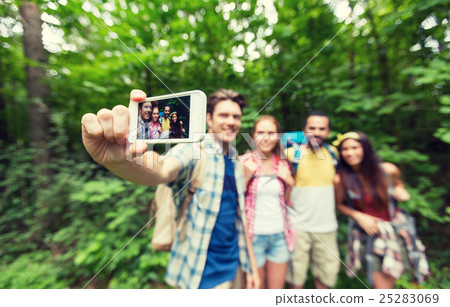 friends with backpacks taking selfie by smartphone 25283069