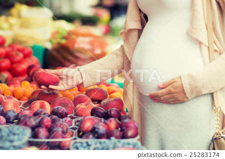 pregnant woman choosing fruits at street market pregnant woman choosing fruits at street market 25283174