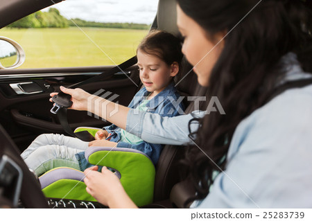 happy woman fastening child with seat belt in car 25283739