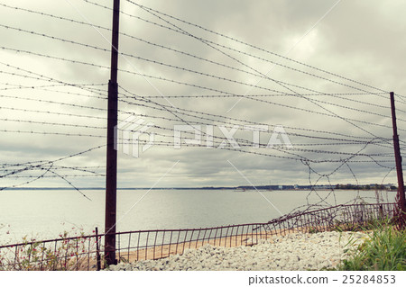 barb wire fence over gray sky and sea 25284853
