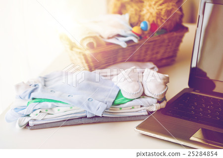 close up of baby clothes, toys and laptop 25284854