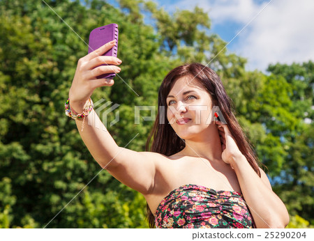 young girl making selfie in a park young girl making selfie in a park 25290204