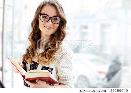 Cute girl with brown curly hair holding book 25299649