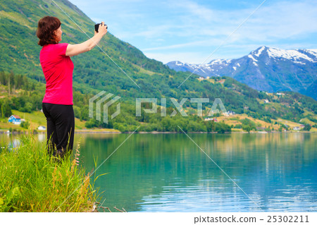 Tourist taking photo at norwegian fjord 25302211
