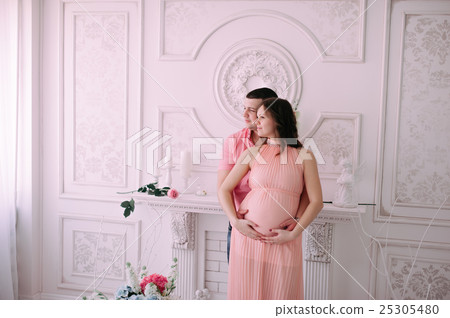 Family waiting for baby's birth. A pregnant woman and her husband wearing white clothing Family waiting for baby's birth. A pregnant woman and her husband wearing white clothing 25305480