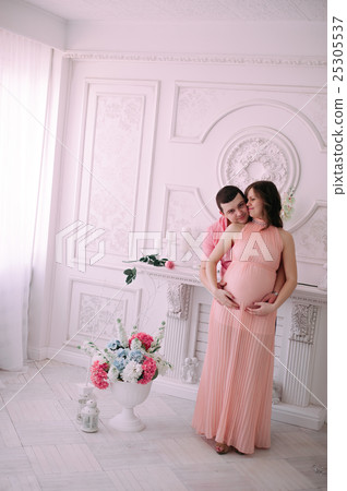 Family waiting for baby's birth. A pregnant woman and her husband wearing white clothing Family waiting for baby's birth. A pregnant woman and her husband wearing white clothing 25305537