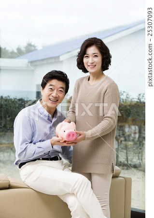 Happy Middleaged Asian Couple Holding a Piggy Bank Happy Middleaged Asian Couple Holding a Piggy Bank 25307093