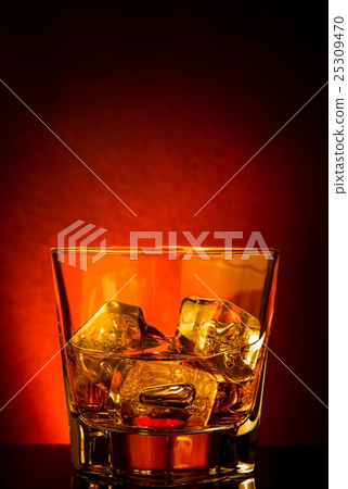 glass of whiskey on black table with reflection, red tint atmosphere 25309470