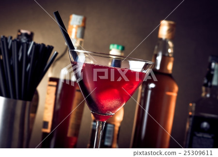 red cocktail into a glass with ice and straw red cocktail into a glass with ice and straw 25309611