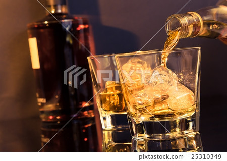 barman pouring whiskey in front of whiskey glass and bottle 25310349