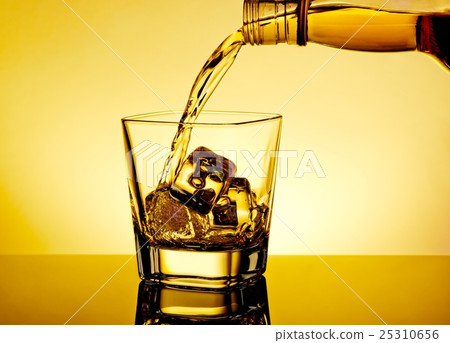 barman pouring whiskey in the glass on table with reflection, warm tint atmosphere 25310656