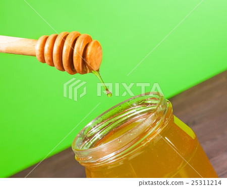 honey jar on wood table and green background with wooden honey dipper on top with drop honey honey jar on wood table and green background with wooden honey dipper on top with drop honey 25311214