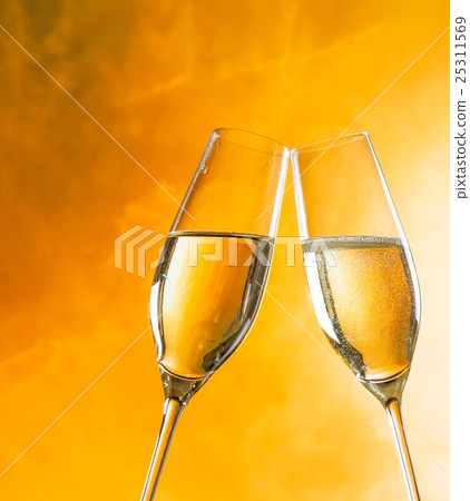 a pair of champagne flutes with golden bubbles on golden light background 25311569
