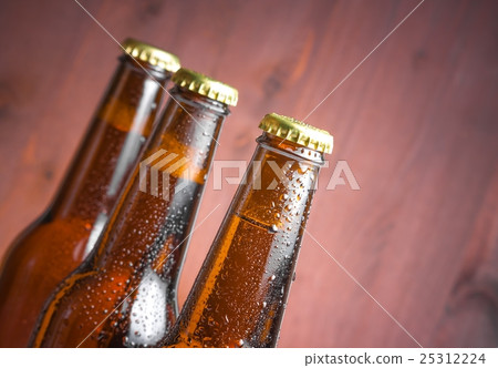three tilted bottles of fresh beer with drops and space for text 25312224