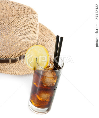 glass of fresh coke with straw in front of summer hat, summer time 25312482