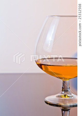 snifter of brandy in elegant typical cognac glass on light background snifter of brandy in elegant typical cognac glass on light background 25312508