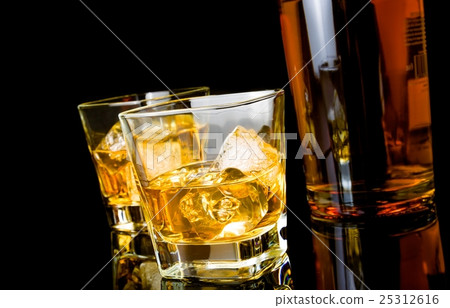 whiskey with ice in glasses near bottle on black background 25312616