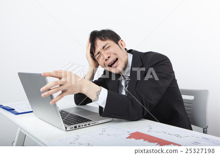 A businessman holding a head in front of a personal computer A businessman holding a head in front of a personal computer 25327198