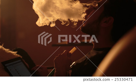 man smokes a hookah and uses tablet 25330471