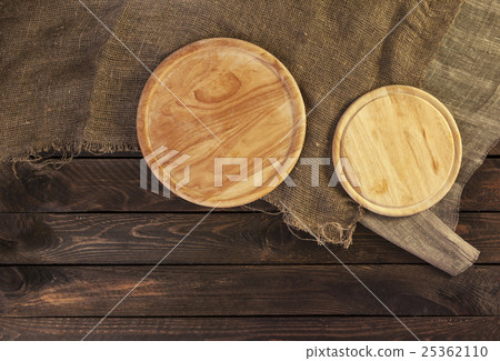 Round cutting board on dark wooden table 25362110