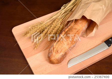 French bread and wheat and bread cutting knife on tasty cutting board 25367400