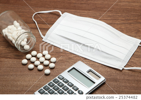White pills, masks and calculators spilling from a collapsed transparent bottle White pills, masks and calculators spilling from a collapsed transparent bottle 25374482