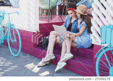 girls looking into laptop while resting on a 25390278