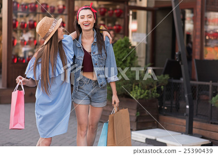 two pretty girls standing on the street with bags 25390439
