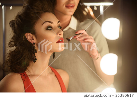 Skillful visagist applying powder on model face Skillful visagist applying powder on model face 25390617