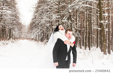 Groom giving piggyback ride to bride in winter Groom giving piggyback ride to bride in winter 25400642