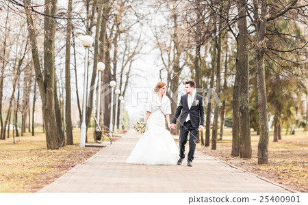 happy bride and groom walking in the autumn park happy bride and groom walking in the autumn park 25400901
