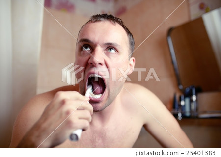 Man brushes teeth in bathroom an electric brush Man brushes teeth in bathroom an electric brush 25401383