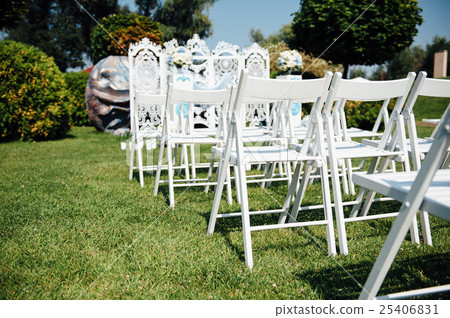 Rows of white folding chairs on lawn 25406831