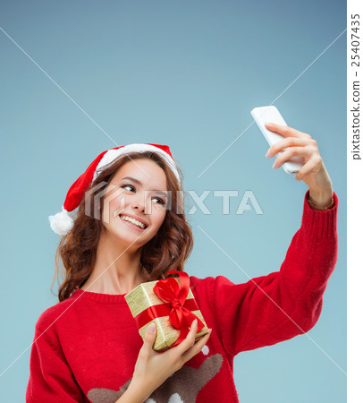 Girl dressed in santa hat with a Christmas gift Girl dressed in santa hat with a Christmas gift 25407435