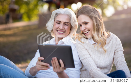 smiling women sitting on the ground and using 25408017