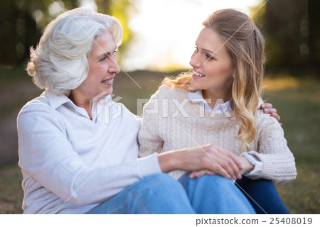 Two charming smiling women hugging and sitting on Two charming smiling women hugging and sitting on 25408019