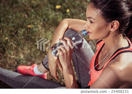 Beautiful girl drinking water after training 25408231