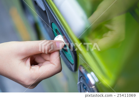Hand inserting coin into a vending machine. 25411069